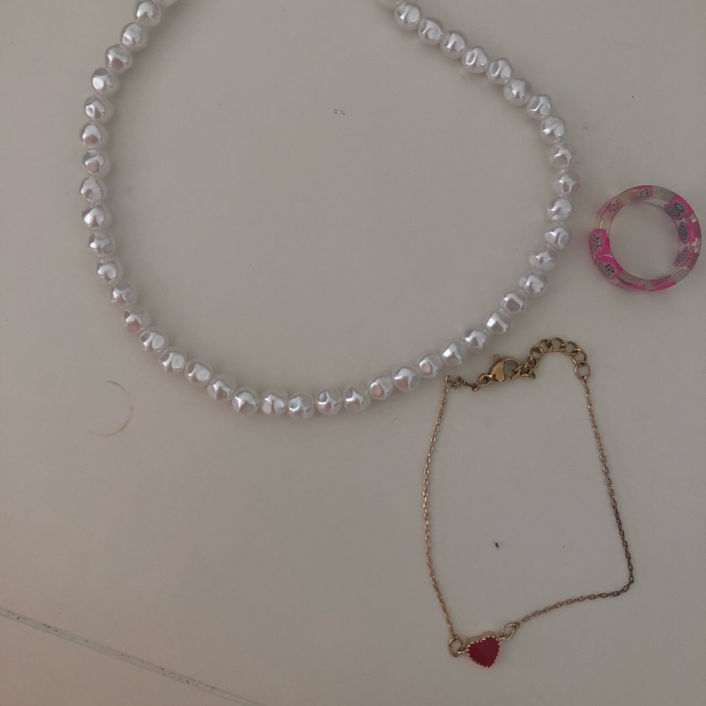 pearl necklace, gold bracelet with heart, ring with fruit on it